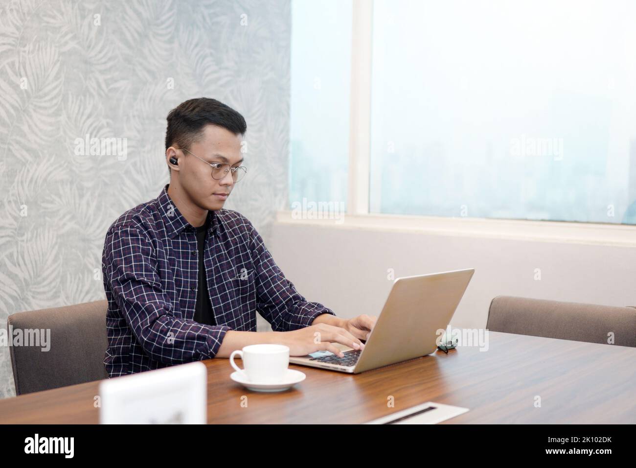 Serious office employee sitting at work desk with laptop, preparing