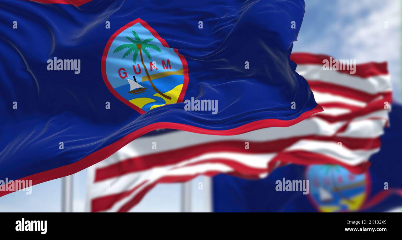 Flags of Guam waving in the wind with the US flag on a clear day. Guam is an organized, unincorporated territory of the United States in the Micronesi Stock Photo