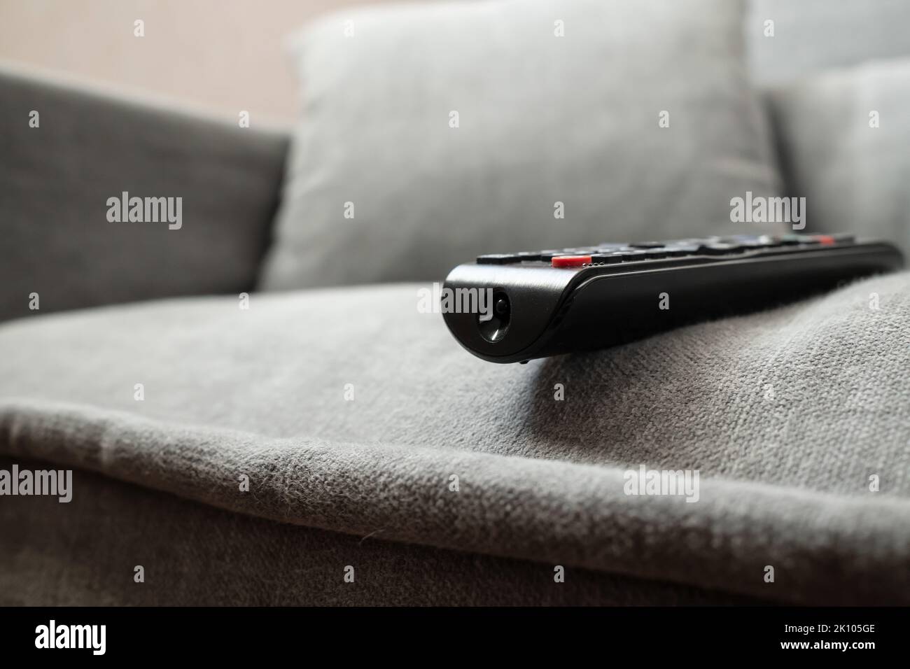 TV remote is accidentally left on the edge of the sofa and may fall. Concept of careless attitude to things.  Stock Photo