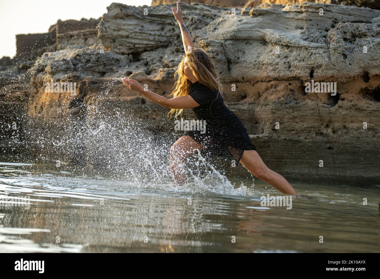 middle-aged woman dancing and throwing water in the air, Maioris beach, llucmajor, Majorca, Balearic Islands, Spain Stock Photo
