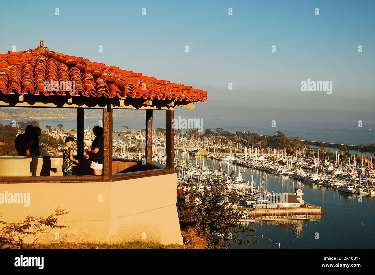 Friends enjoy a shaded seat under a red tiled gazebo that overlooks the beautiful harbor of Dana Point, Colifornia Stock Photo