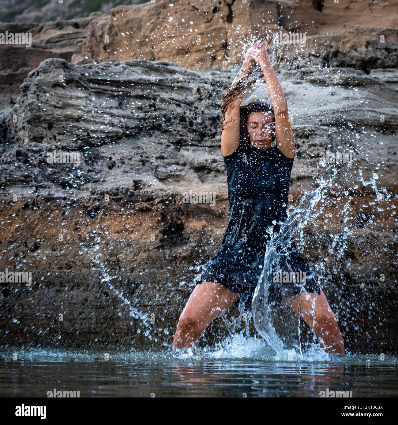 middle-aged woman dancing and throwing water in the air, Maioris beach, llucmajor, Majorca, Balearic Islands, Spain Stock Photo