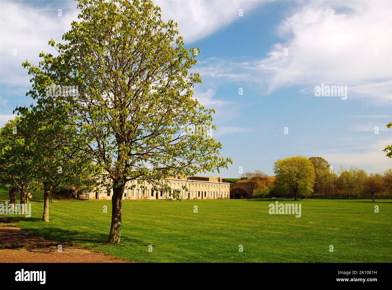 A line of trees grow on the edge of the expansive parade grounds of Fort Warren, a Revolutionary era fortress in the Boston Harbor Islands Stock Photo