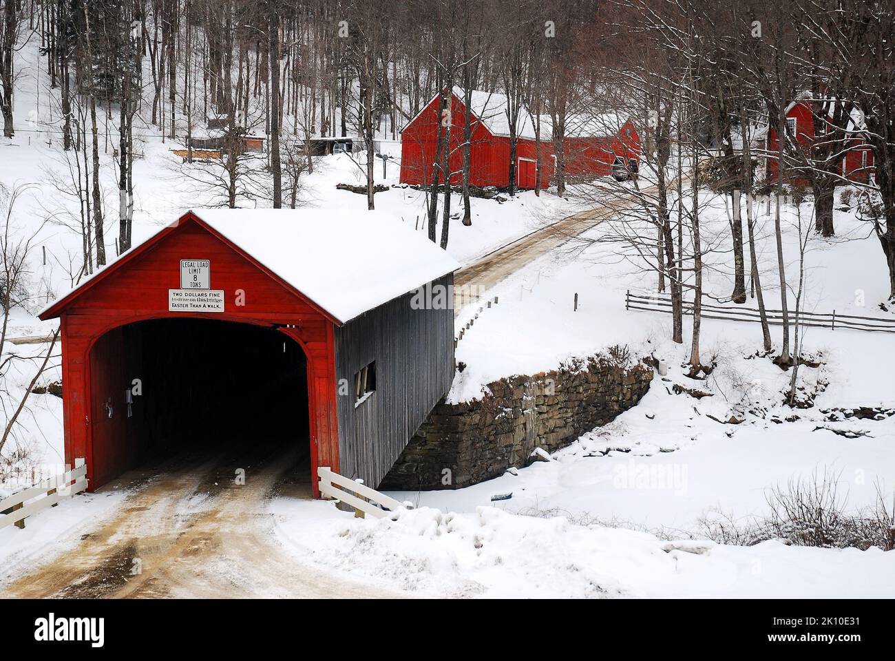 A country road travels through the red Green River Covered Bridge in a snow covered winter landscape in Guilford, Vermont, New England Stock Photo