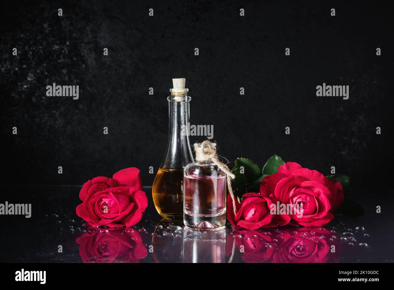 Bottles of perfume and red roses on a black background. Stock Photo