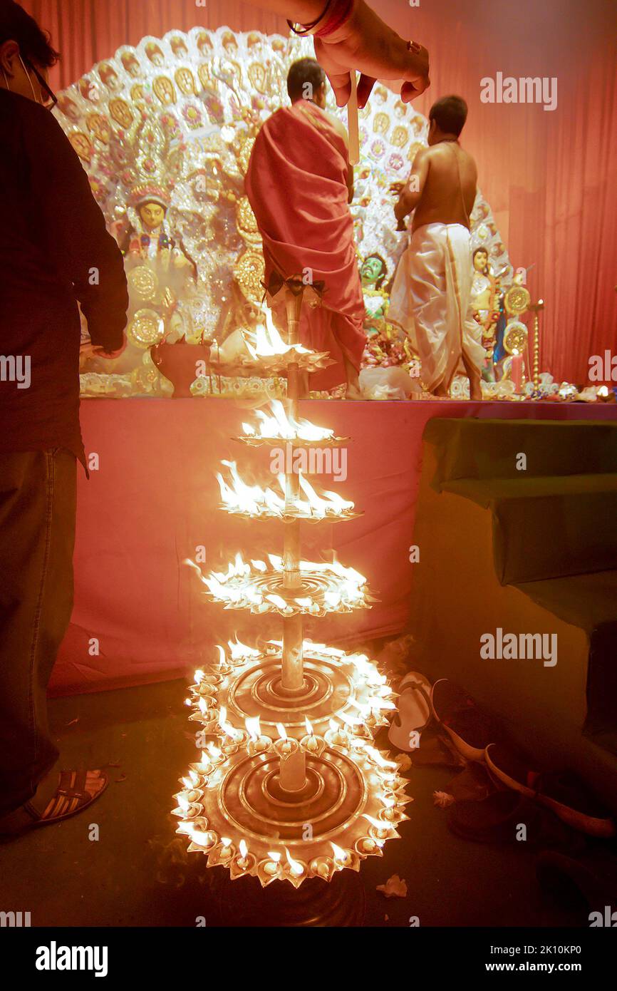 Howrah, India - October 15th, 2021 : Devotee lighting up 108 lamps during Sandhi Puja, the sacred juncture of Ashtami, eighth day and Nabami. Stock Photo