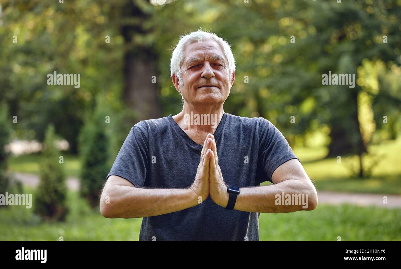 Older active hoary calm man do meditation practice with eyes closed