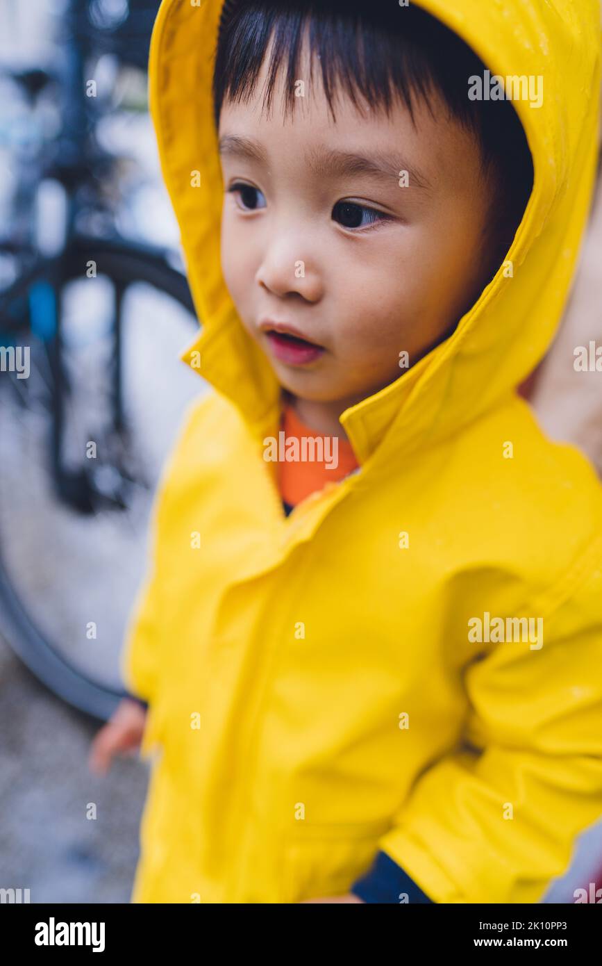 A young boy wearing a yellow raincoat Stock Photo