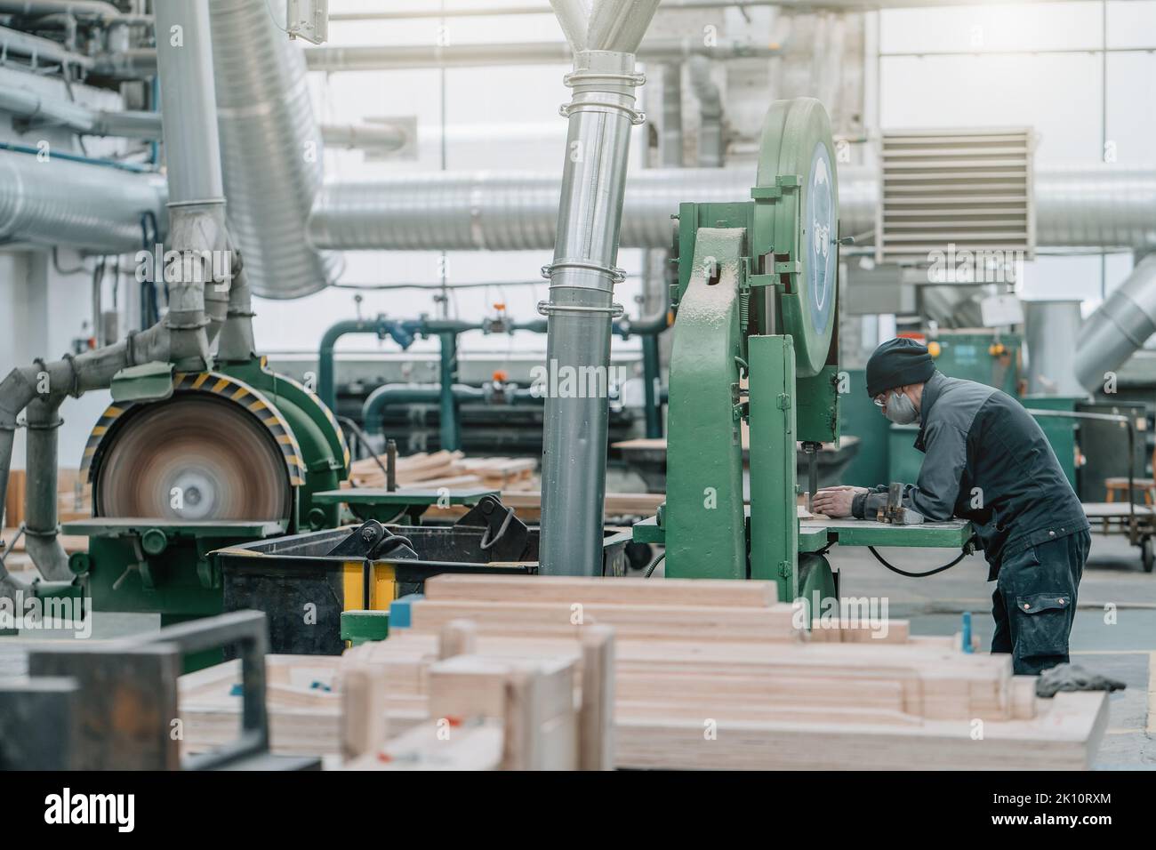 Unrecognizable worker inside huge woodwork factory workshop with stacks of wood. Stock Photo