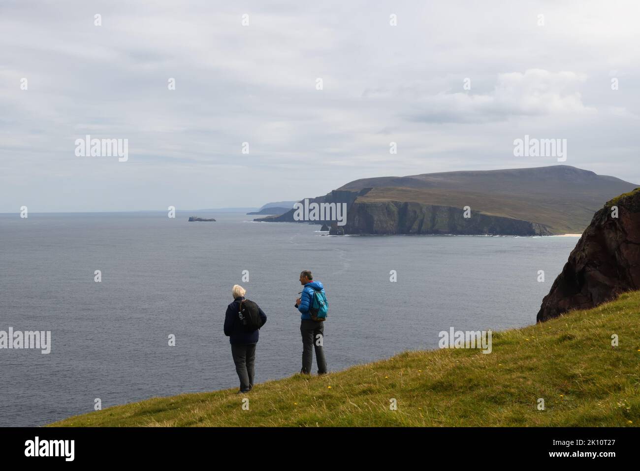 Tourists survey the cliffs and Atlantic Ocean from Cape Wrath on the north west coastline of Scotland, UK Stock Photo