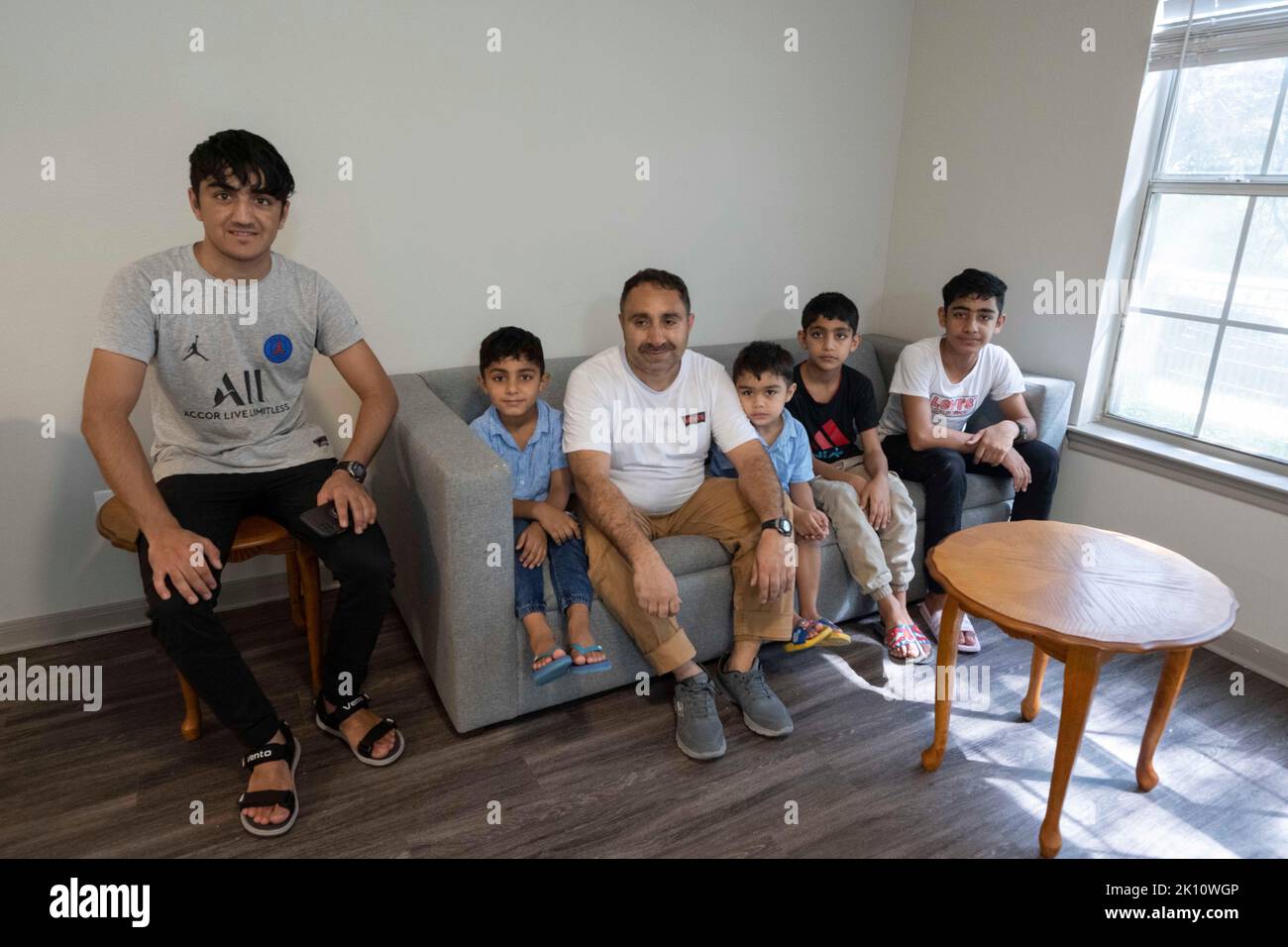 The male members of an Afghanistan refugee family pose for a picture after moving furniture into an apartment in north Austin, more than a year after they left their war-torn homeland in 2021. The family of ten spent 13 months in a Dubai refugee camp before being relocated to the U.S. via Turkey. ©Bob Daemmrich Stock Photo