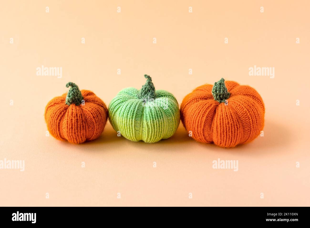Knitted orange and green pumpkins on an orange background, autumn ...