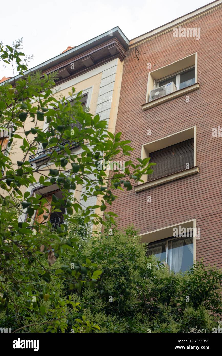 Facades of urban residential buildings with gardens and lots of trees Stock Photo