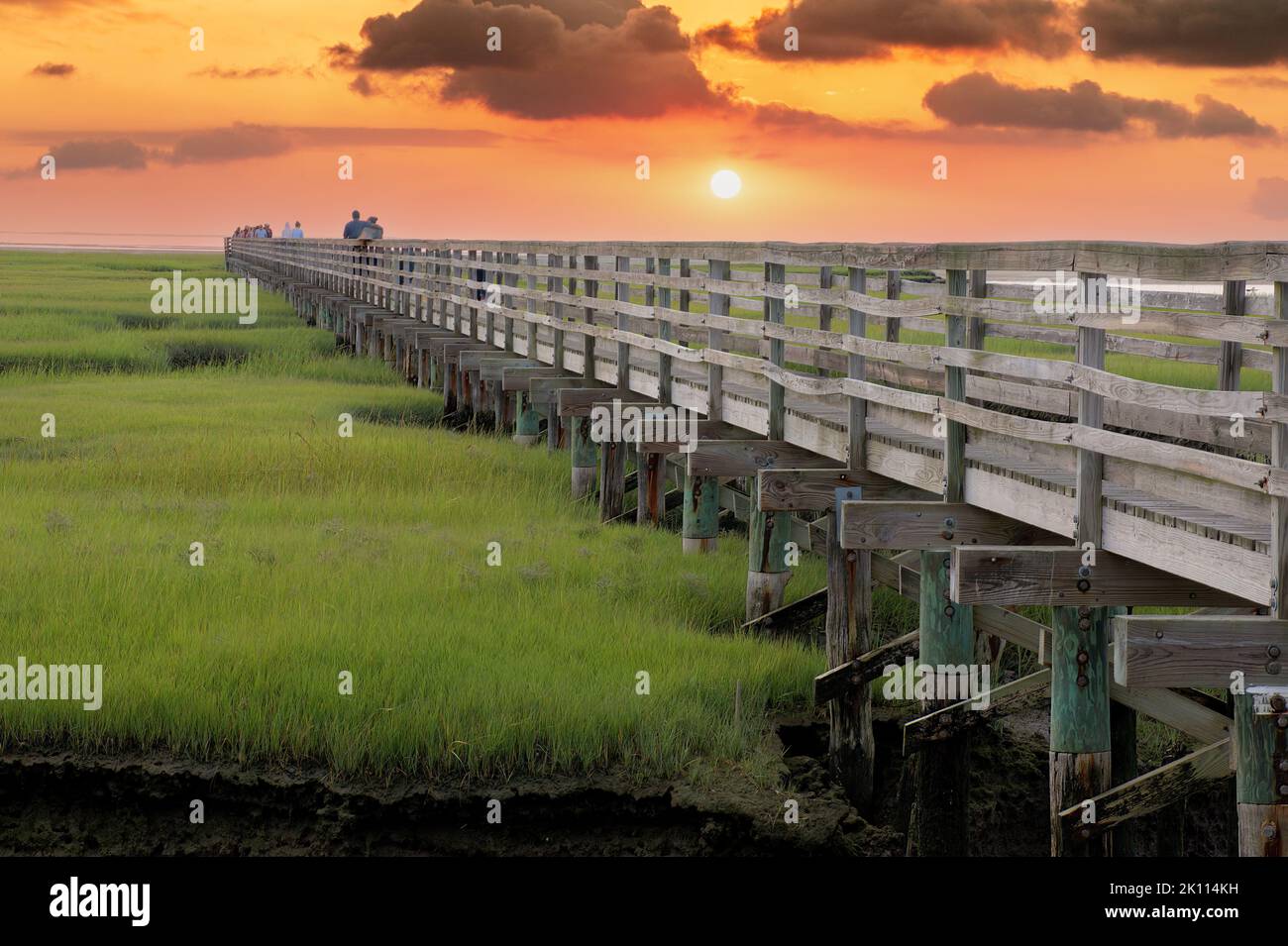 Scenic view of colorful Cape Cod sunset over raised wooden boardwalk spanning protected saltwater marsh at Grays Beach, Yarmouth Port, Massachusettes. Stock Photo
