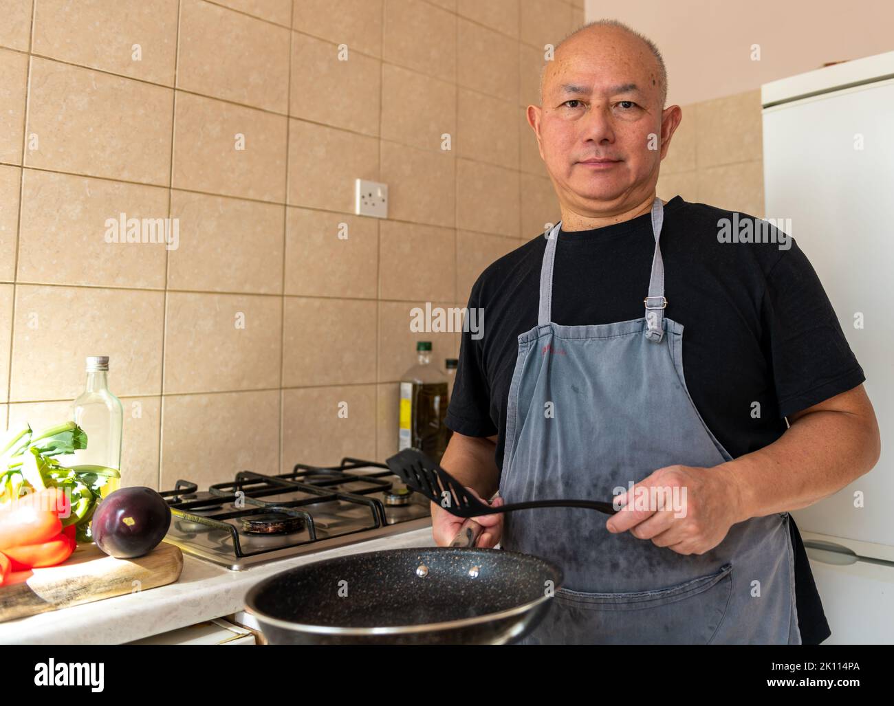 Portrait of a senior man, cook, making a meal in the kitchen. Stock Photo