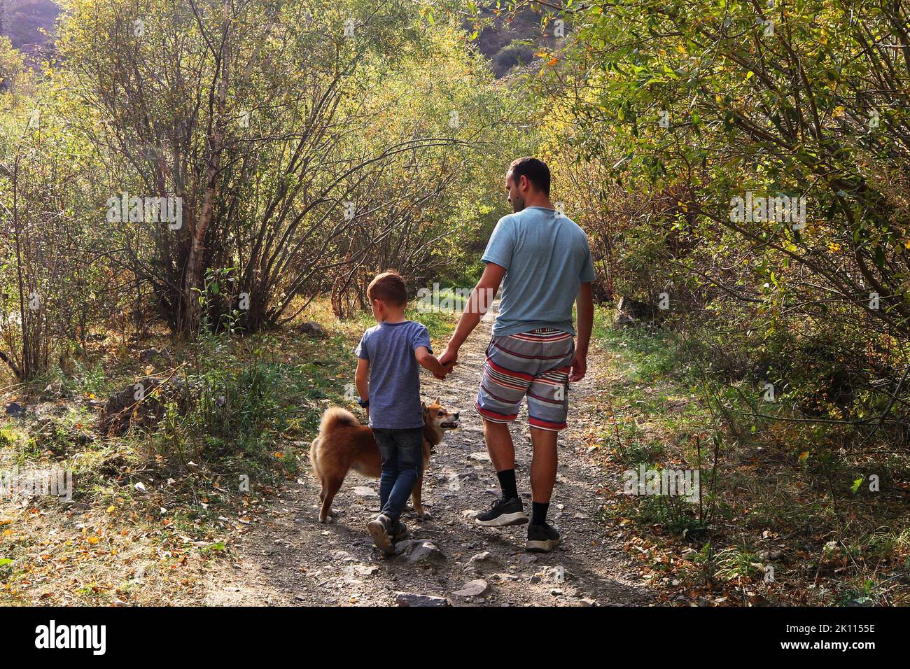 dad with his son and dog walking in the autumn forest Stock Photo