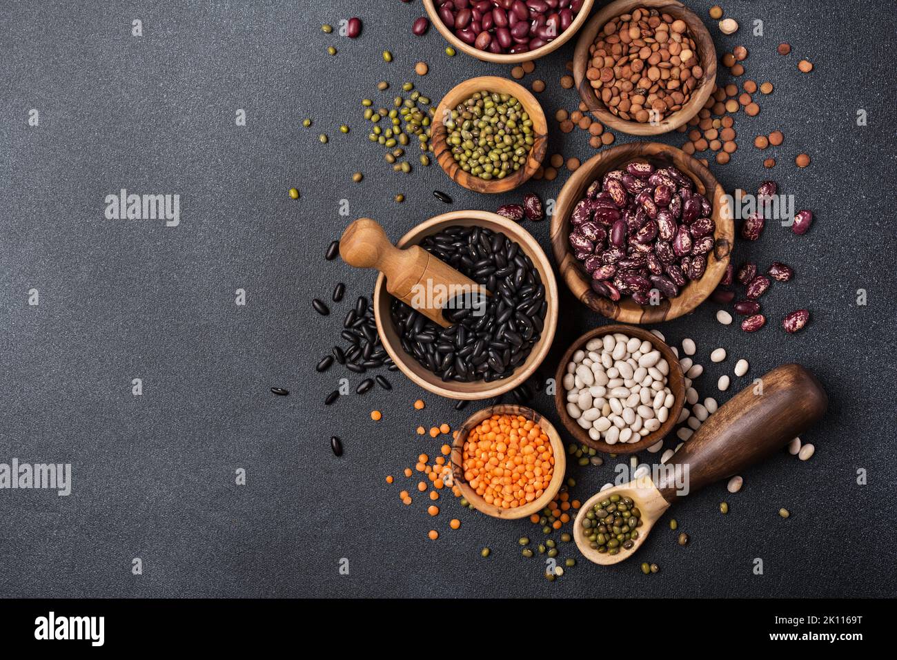 Top view of different beans, lentils, mung or maash in bowls on dark concrete background Stock Photo