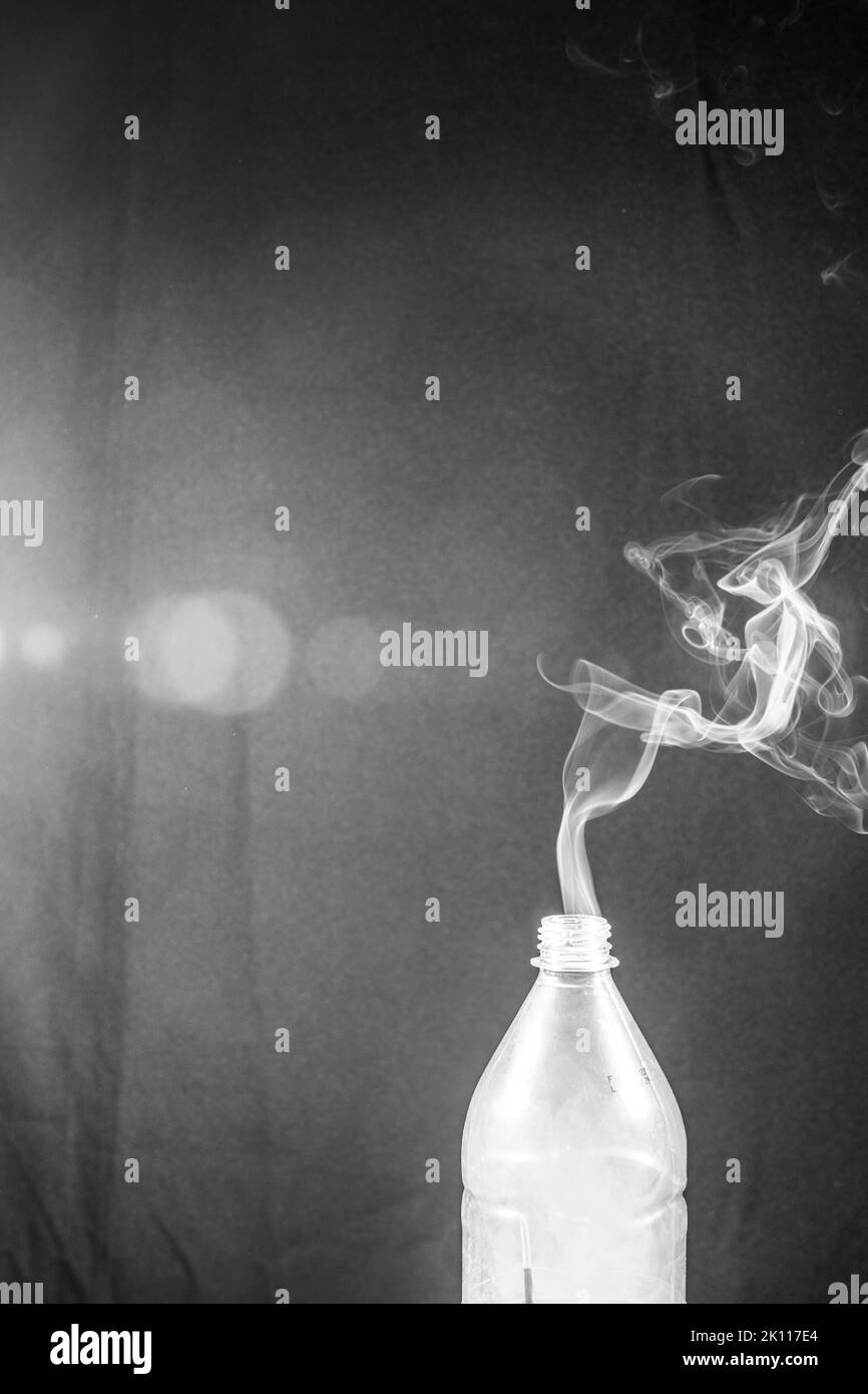 Smoke coming out of a plastic bottle against a black background with