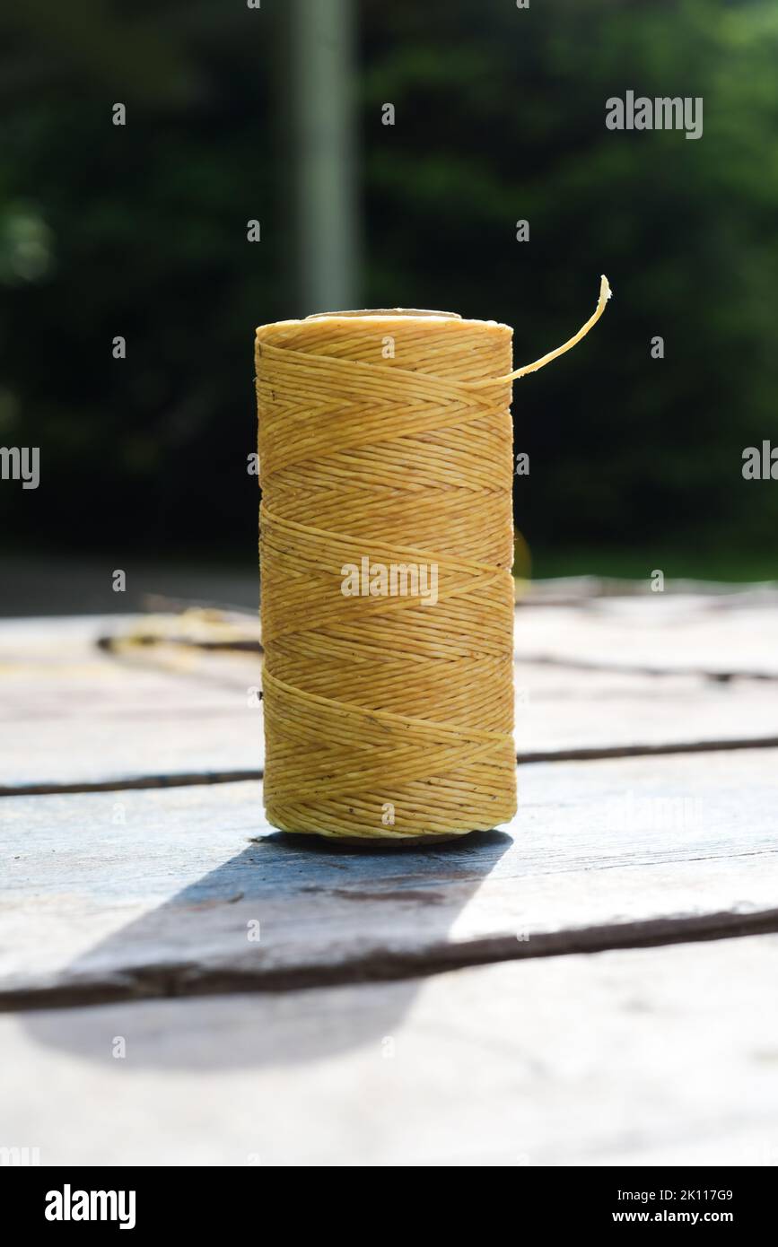 Spool of waxed thread on wooden background Stock Photo