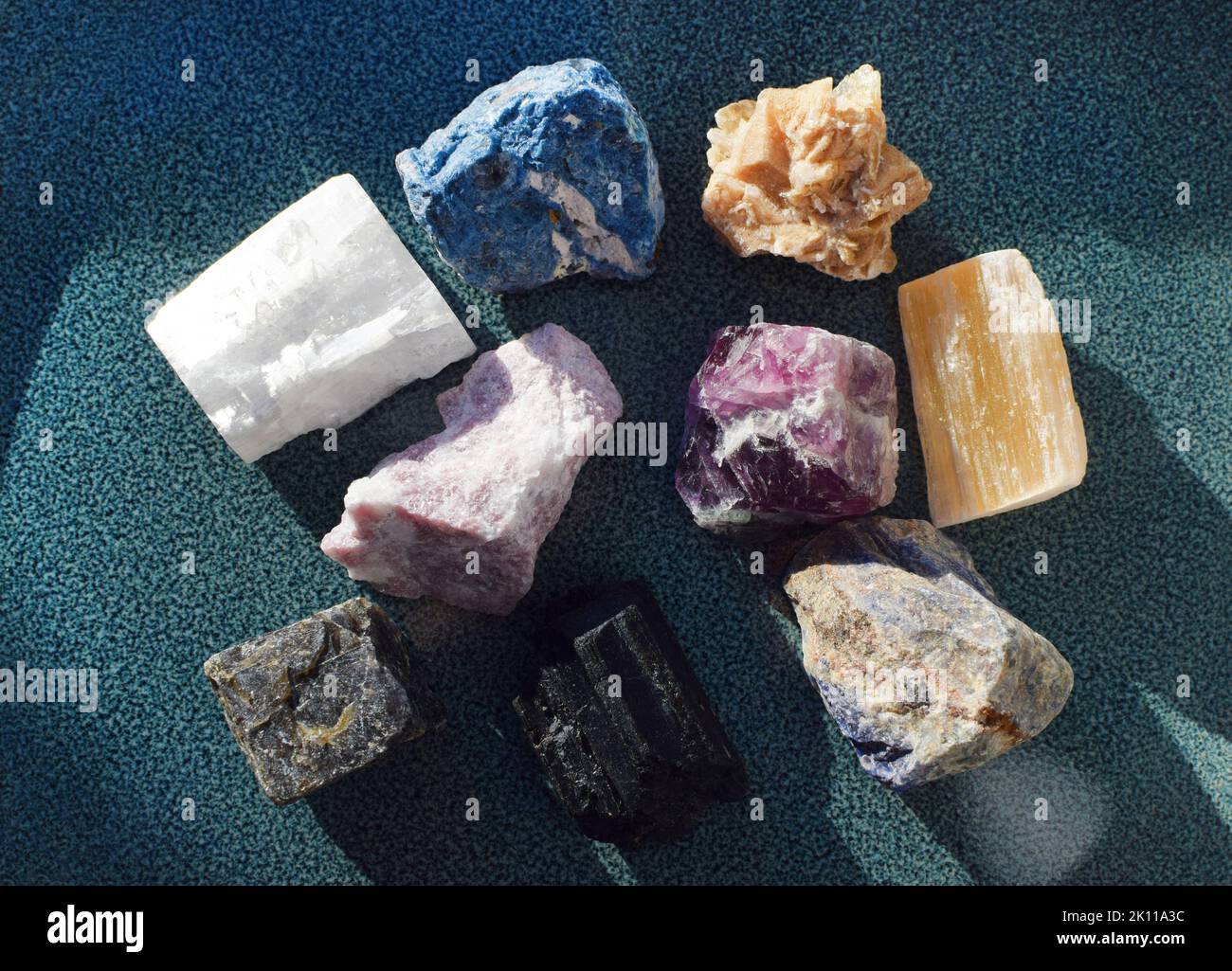 Multi-colored gemstones, minerals on a blue ceramic plate. Rose quartz, turquoise, labradorite, sodalite, fluorite, red gypsum, black tourmaline, scho Stock Photo
