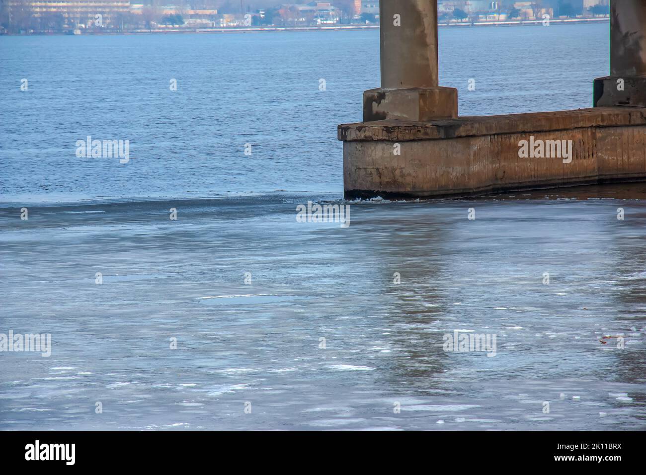 In the spring, a thin ice floe drifts downstream and floats past the bridge support. Stock Photo