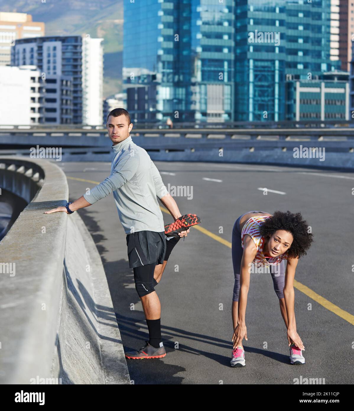 Running is always better with a partner. Portrait of two friends stretching together before a run through the city streets. Stock Photo