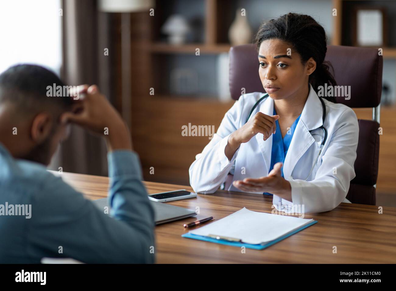 Black woman doctor having conversation with upset sick man patient ...