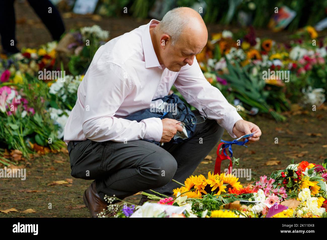 London, UK. 14th Sep, 2022. As crowds of people came to London to watch Her Majesty the Queen's coffin being transported to the Palace of Westminster, a man is pictured as he looks at the condolence cards and flowers that have been left in Green Park, London. Credit: Lynchpics/Alamy Live News Stock Photo