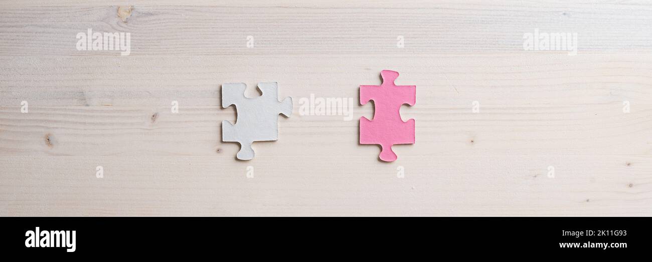 Wide view image of two matching puzzle pieces placed over wooden background with copy space Stock Photo