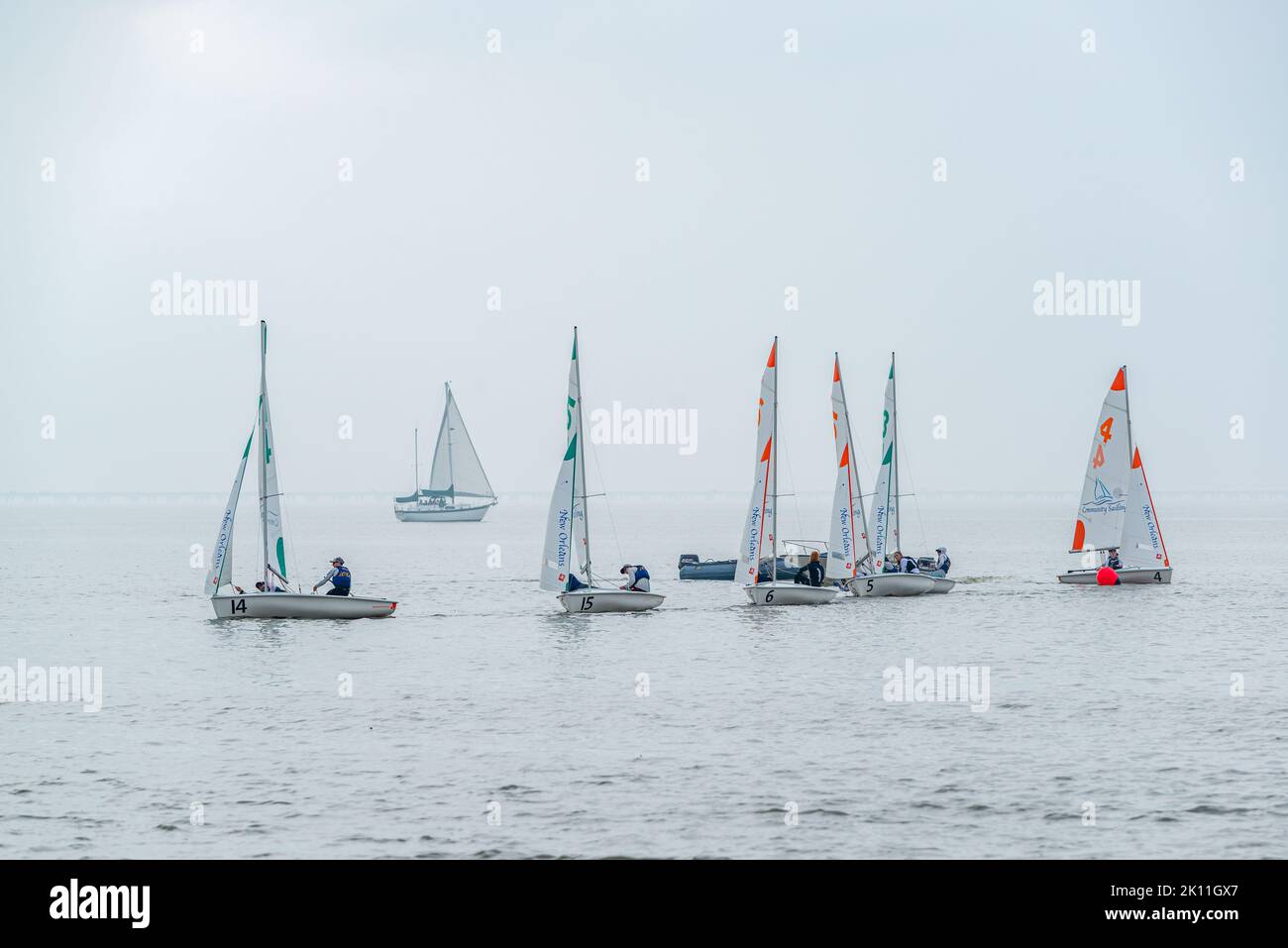 NEW ORLEANS, LA, USA - FEBRUARY 16, 2019: Small sailboat competition on Lake Pontchartrain with larger sailboat and fog in the background Stock Photo