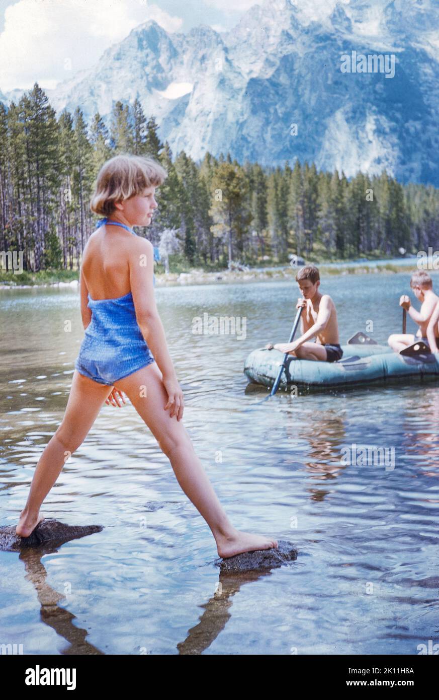 Two Boys in inflatable Raft, Girl standing on two Rocks in Water, Trail Creek Ranch, Wilson, Wyoming, USA, Toni Frissell Collection, August 1958 Stock Photo