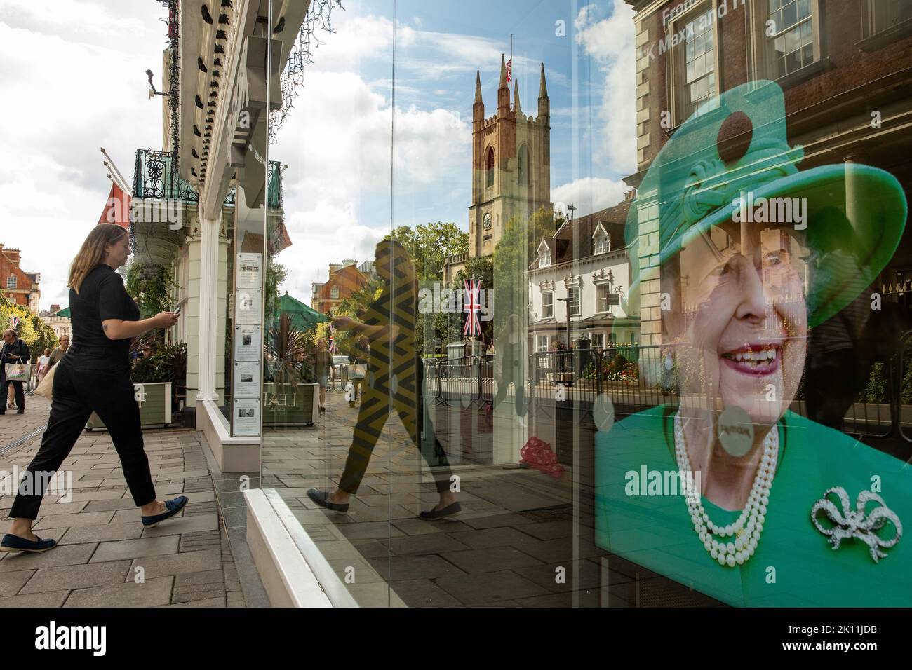 Windsor, UK. 14th September, 2022. Members of the public pass a tribute to Queen Elizabeth II displayed in a shop window. Queen Elizabeth II, the UK's longest-serving monarch, died at Balmoral aged 96 on 8th September after a reign lasting 70 years and will be buried in the King George VI memorial chapel in Windsor following a state funeral in Westminster Abbey on 19th September. Credit: Mark Kerrison/Alamy Live News Stock Photo