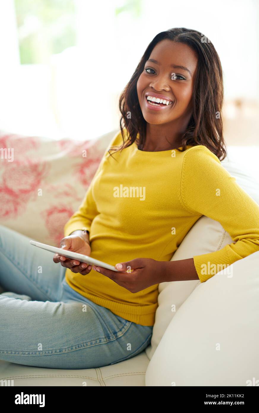 Everything at the touch of a button. Portrait of an attractive young woman using a digital tablet relaxing at home. Stock Photo