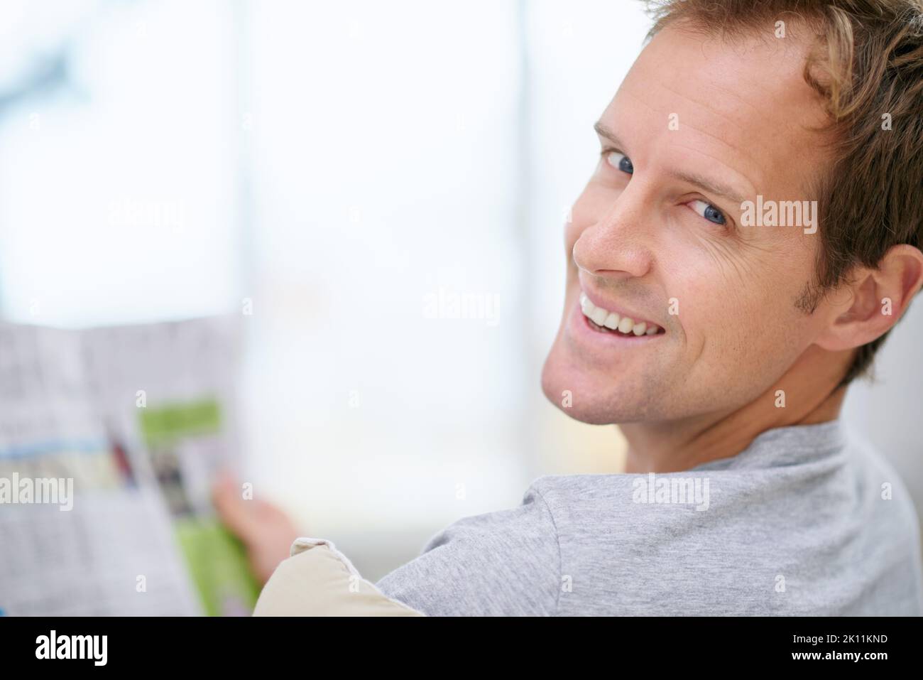 Getting his daily news. Portrait of a handsome man reading a newspaper at home. Stock Photo