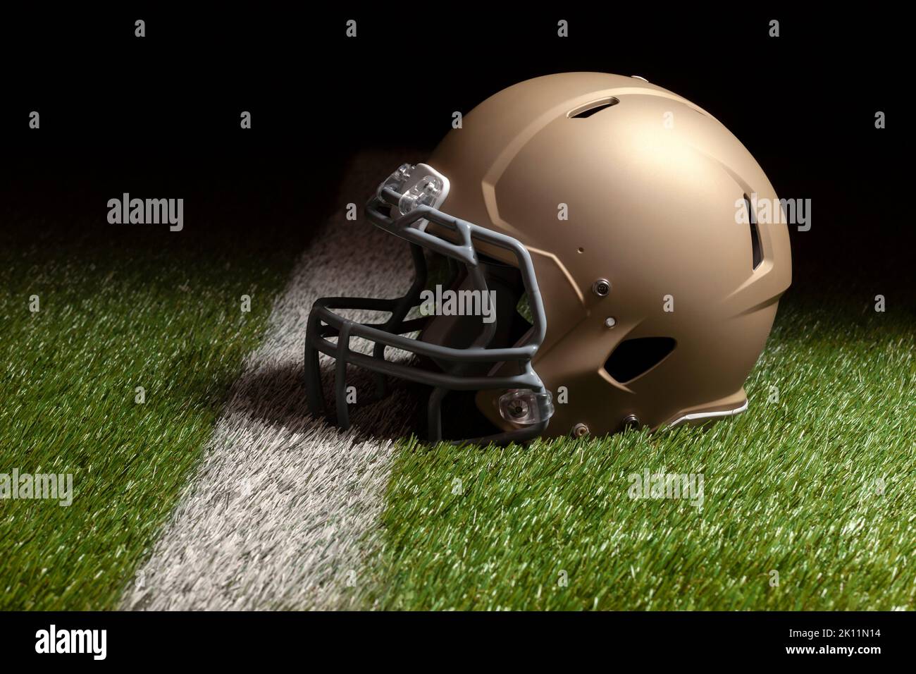Gold football helmet on grass field with stripe and spot lighting Stock Photo