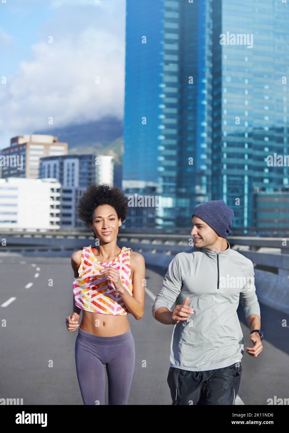 Keep pushing through the miles. two friends jogging together through the city streets. Stock Photo