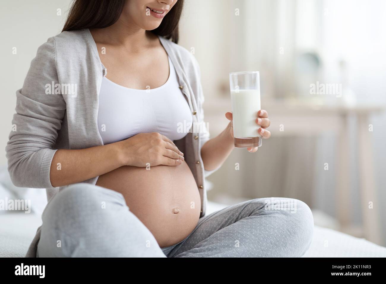 Cropped of expecting lady with big tummy drinking milk Stock Photo