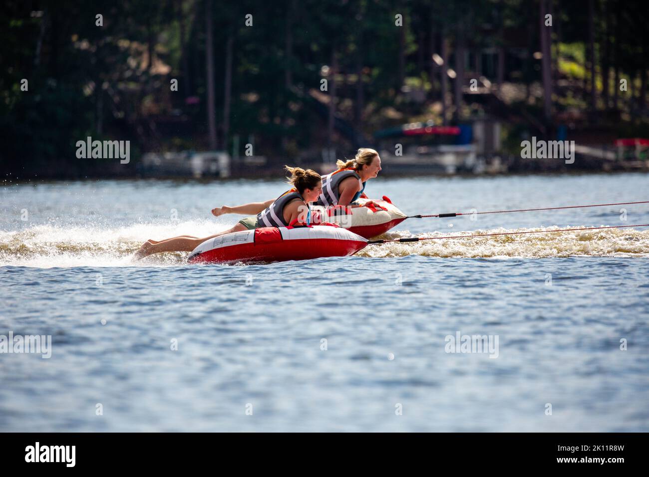Lake Nokomis, Tomahawk, Wisconsin, USA, August, 20, 2022 -  Girls on an inflatable tube being towed across the lake, horizontal Stock Photo