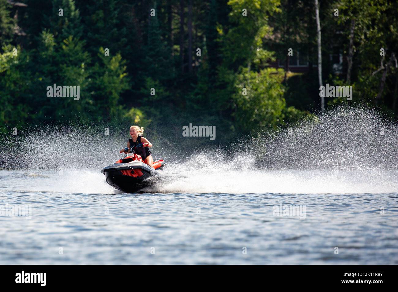 Lake Nokomis, Tomahawk, Wisconsin, USA, August, 20, 2022 - Girl on a jet ski flying across the lake, horizontal Stock Photo