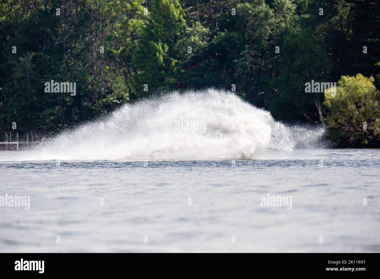 Wave and splash of water is covering the entire jet ski that is making it, horizontal Stock Photo