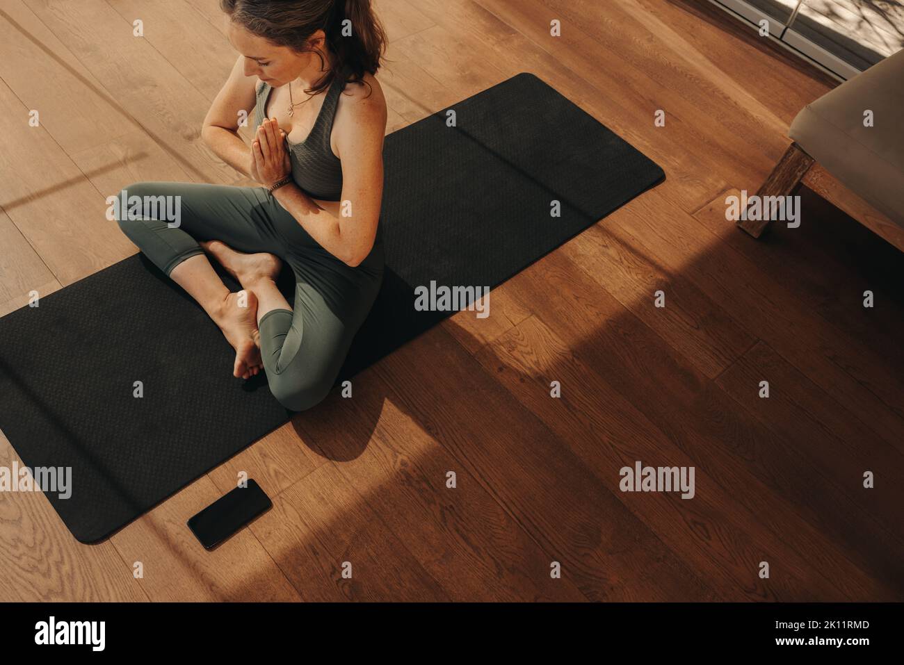 Top view of a mature woman meditating while sitting in prayer position. Senior woman doing a relaxation exercise during a yoga session. Woman practici Stock Photo