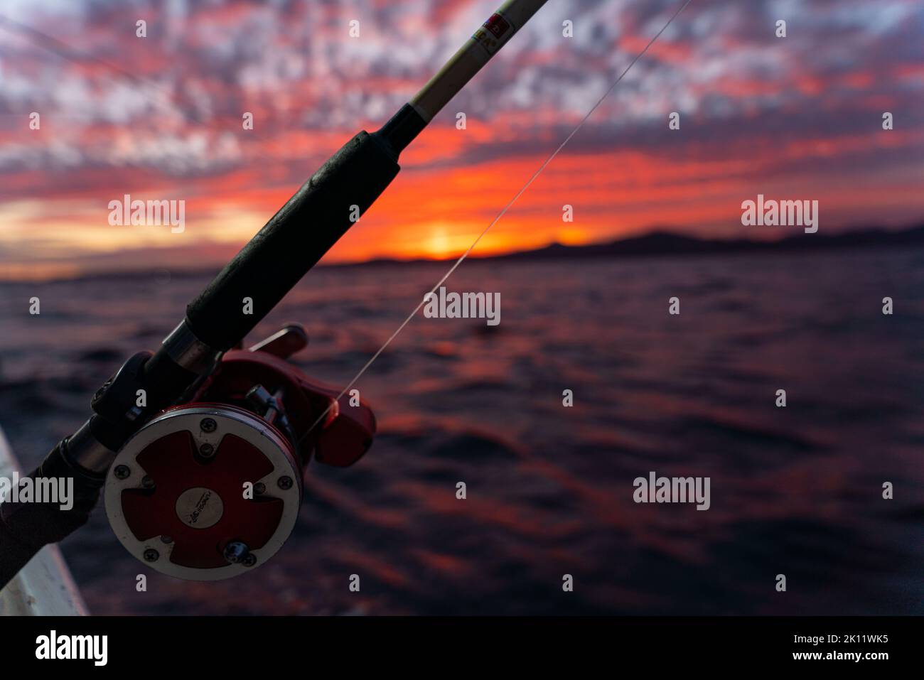 https://c8.alamy.com/comp/2K11WK5/deep-sea-fishing-reel-on-a-boat-during-sunrise-high-quality-photo-2K11WK5.jpg