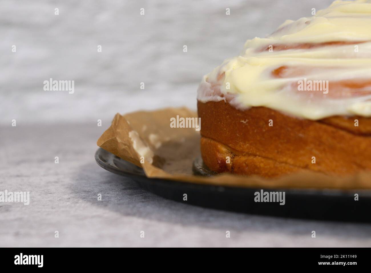 close up of buttercream frosting on cinnamon roll cake, white