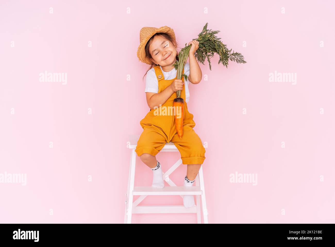 Little girl in an orange jumpsuit is sitting on stepladder. Child