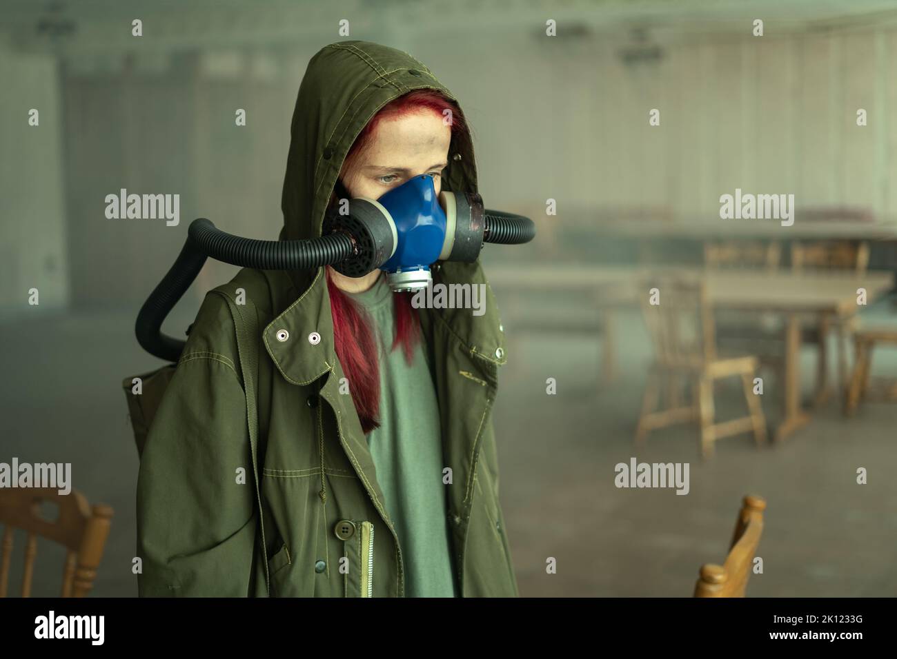 post apocalyptic woman, living in abandoned building wearing gas mask under tattered hood Stock Photo