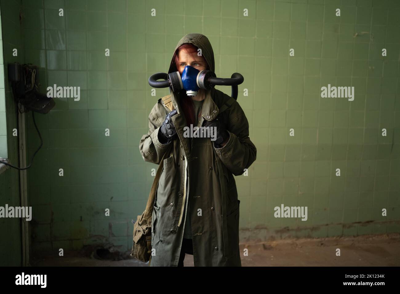 Post apocalypse female survivor in gas mask on wall background. Copy space. Air pollution, environmental disaster Stock Photo