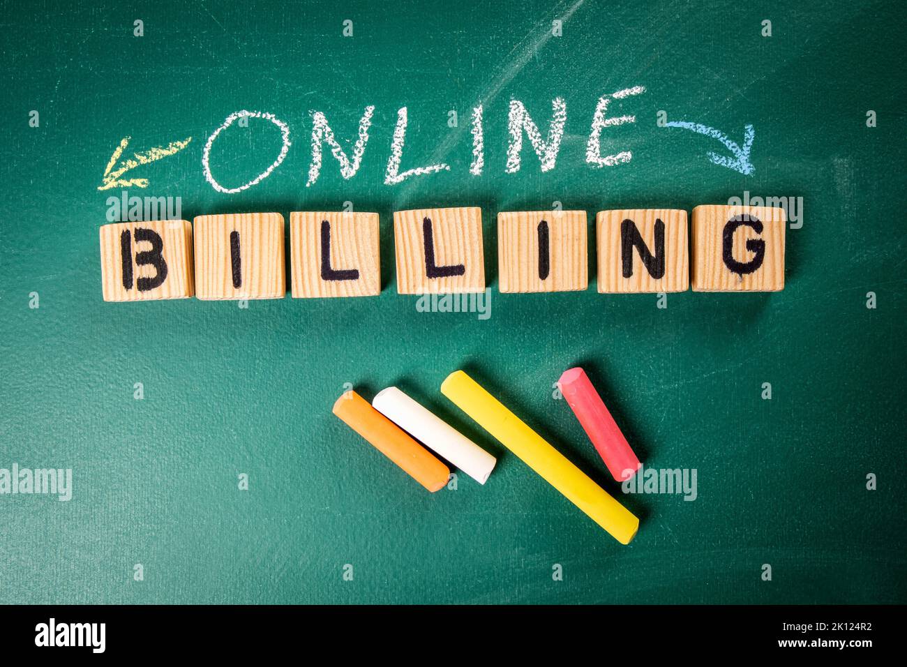 Online Billing concept. Wooden letter blocks and colored pieces of chalk on a green board. Stock Photo