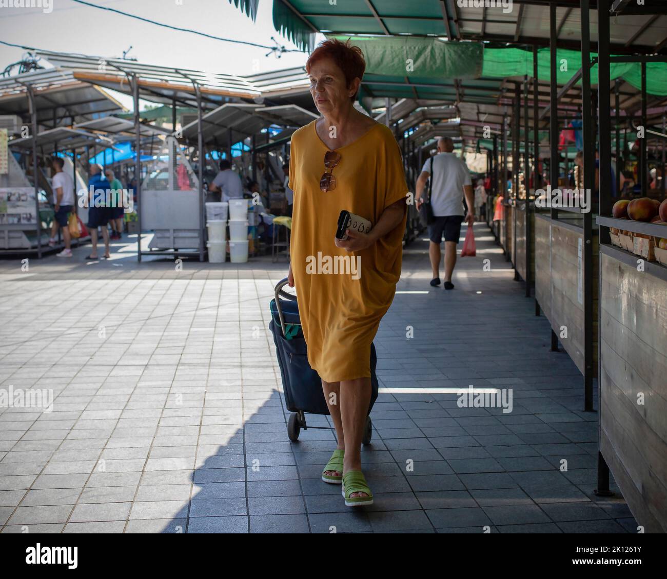 Belgrade, Serbia, Aug 5, 2022: Woman pulling a shopping trolley bag along the farmers' market Stock Photo