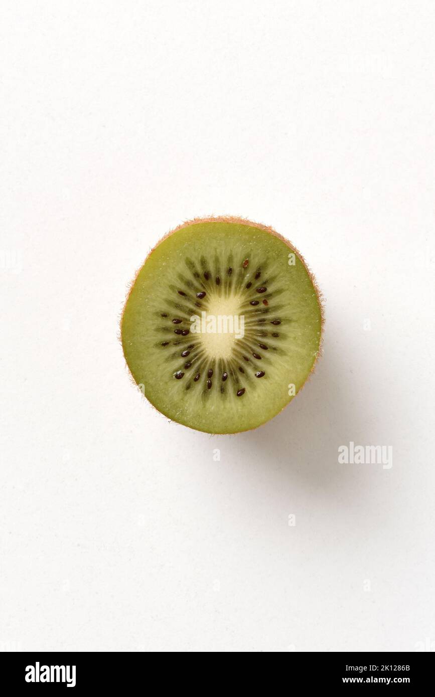 Detail of half ripe kiwi isolated on white table. Top view. Vertical composition. Stock Photo