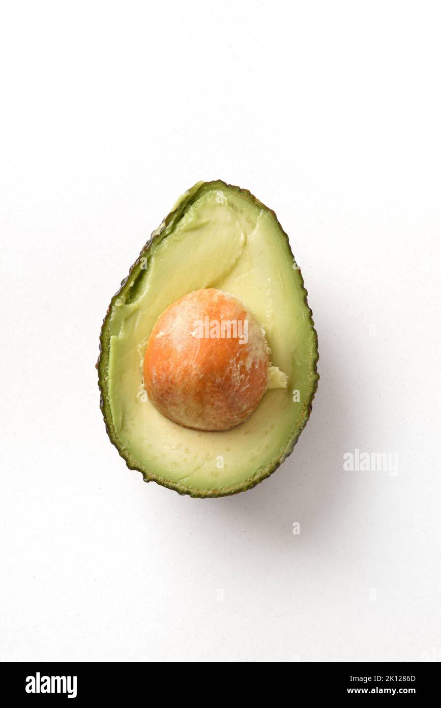 Detail of cut ripe avocado with skin texture isolated on white table. Vertical composition. Stock Photo